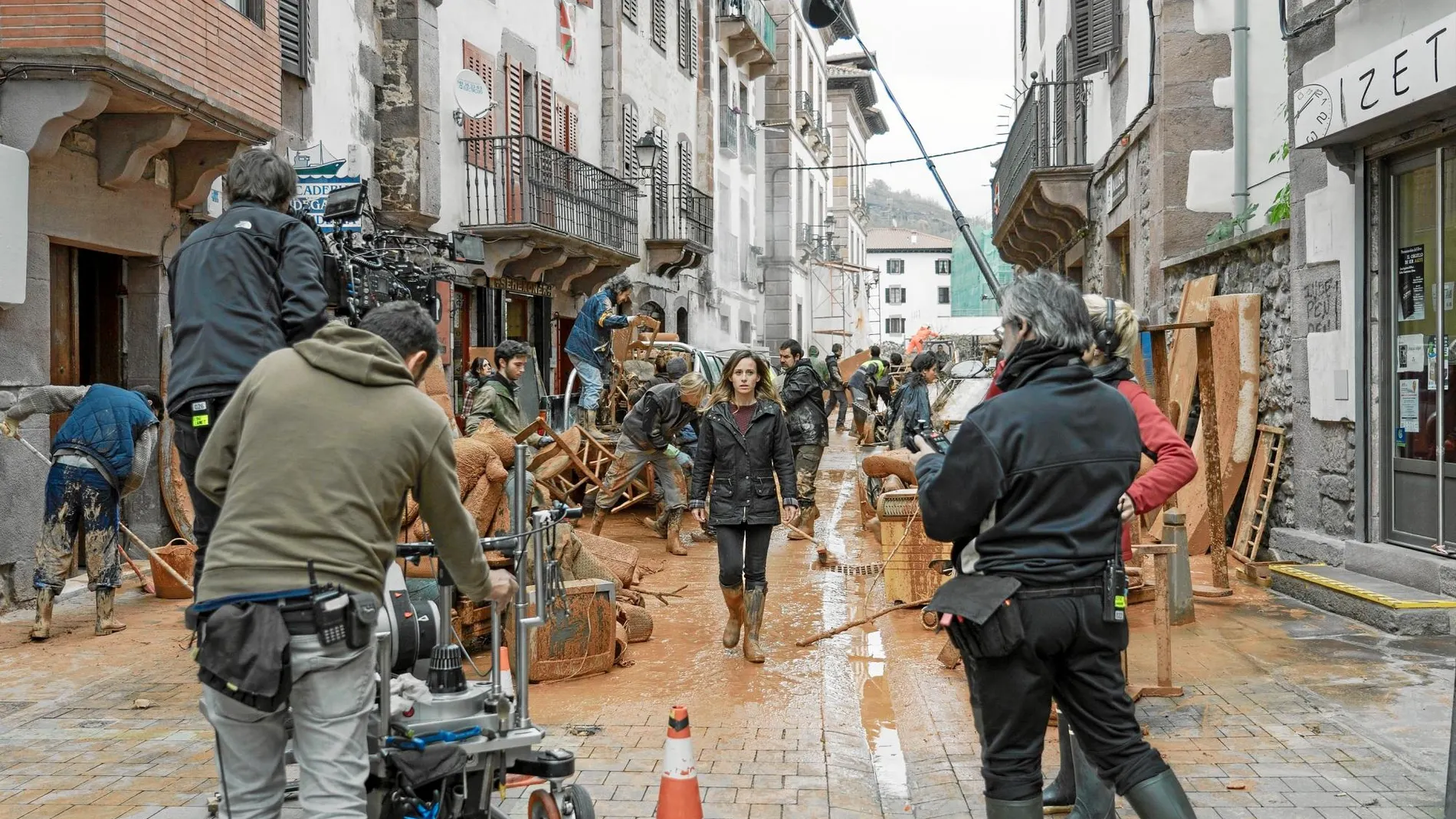 Marta Etura (en el centro) avanza por una calle enlodada en pleno rodaje en Elizondo