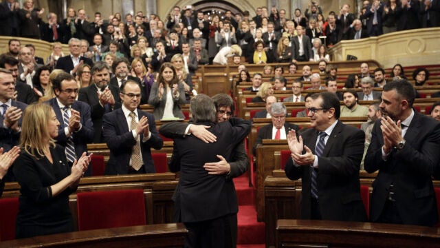 El presidente catalán en funciones, Artur Mas (de espaldas), saluda a Carles Puigdemont, poco antes de comenzar el pleno del Parlament.