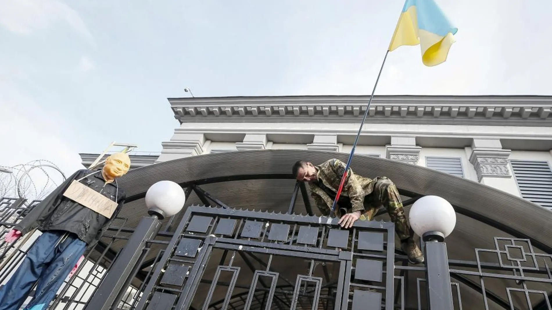 Un manifestante coloca una bandera ucraniana en la puerta de la embajada rusa en Kiev.