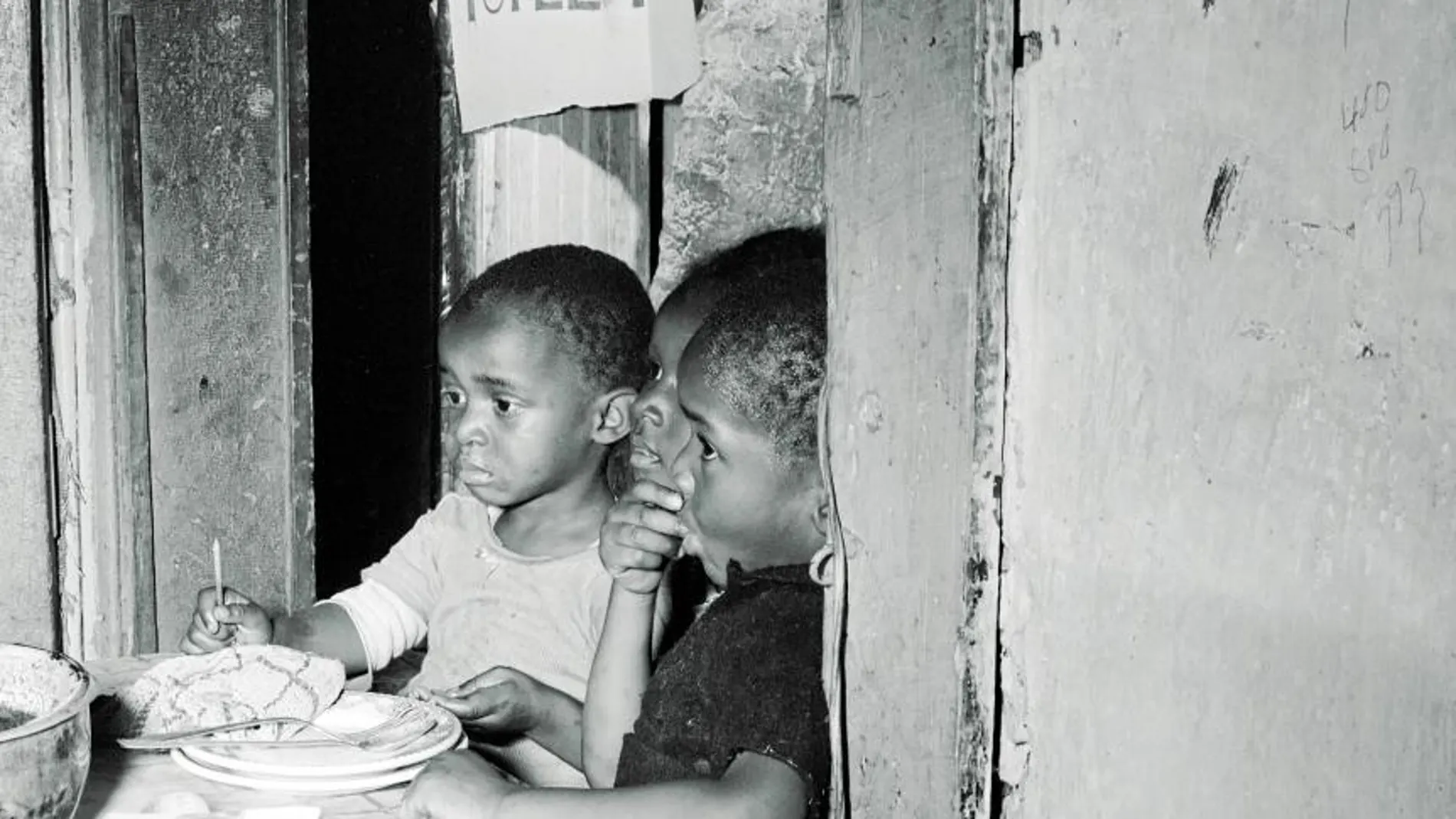 Icónico gueto: tres niños esperan mientras su madre les prepara el desayuno (Washington D. C., 1942) / Gordon Parks
