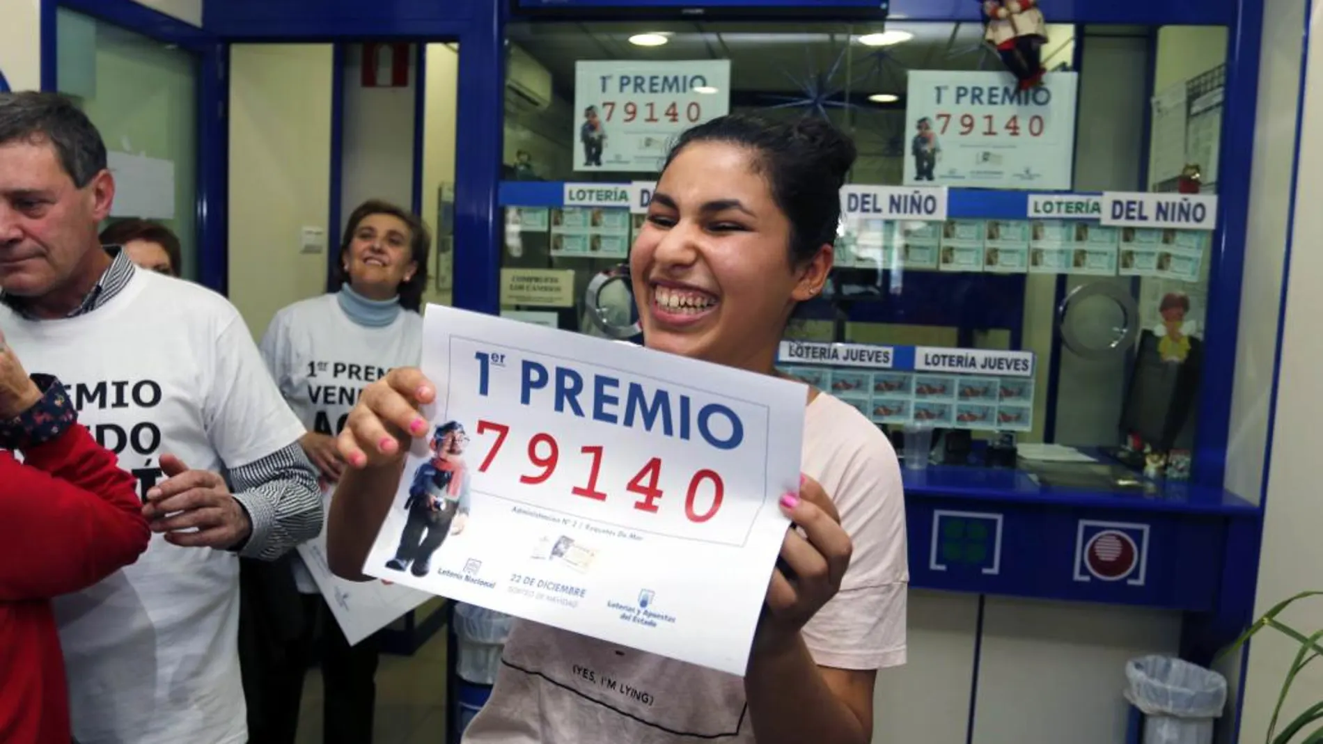 Una joven sonríe con una copia del número 79.140, agraciado con el Gordo de Navidad del Sorteo Extraordinario de la Loteria celebrado hoy y vendido íntegramente en la administracion nº 2 de Roquetas de Mar (Almería)