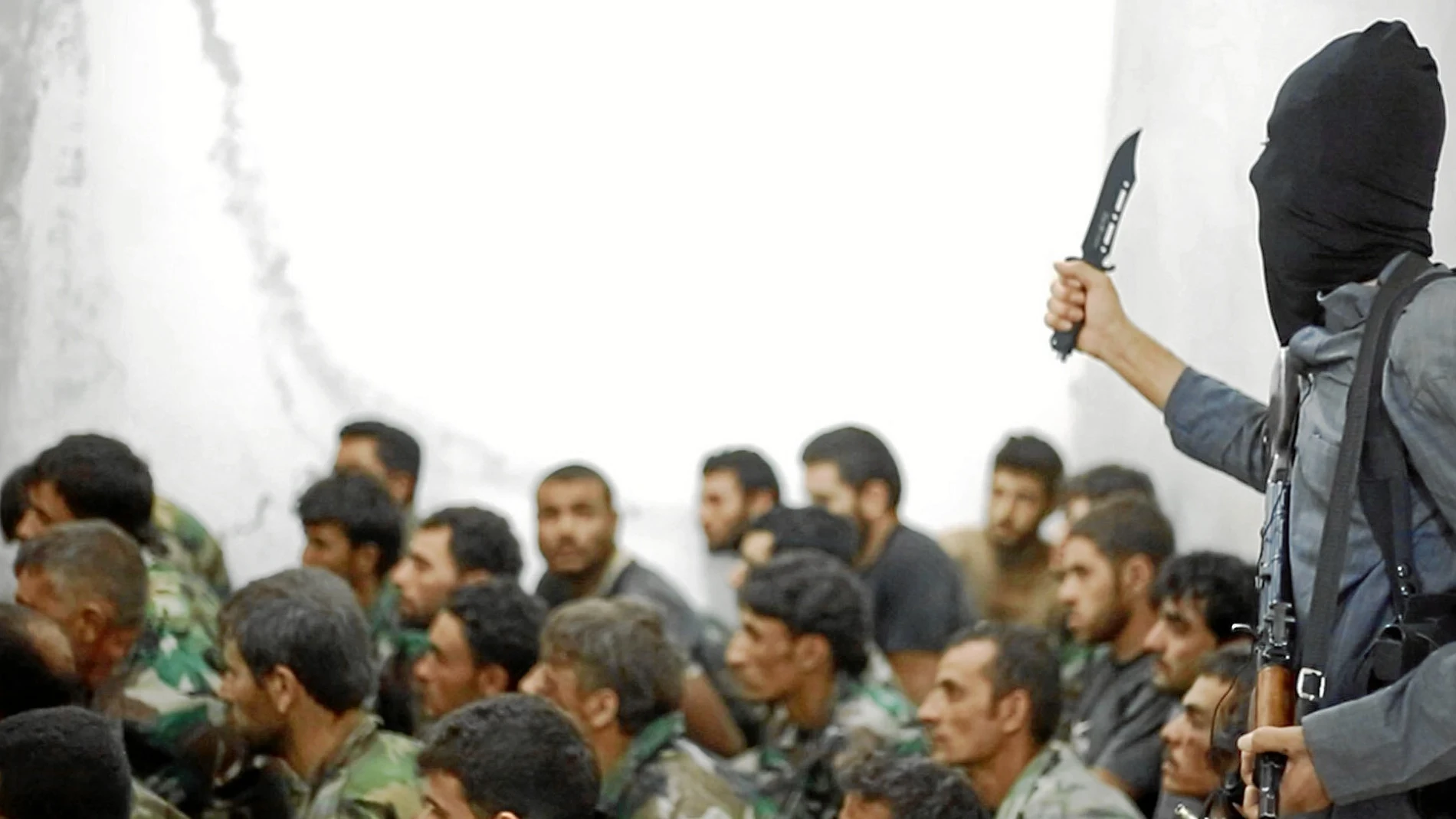 Un miembro del Estado Islámico, en una foto de 2014, amenaza a un grupo de soldados sirios hechos prisioneros tras la batalla de Raqqa / Ap