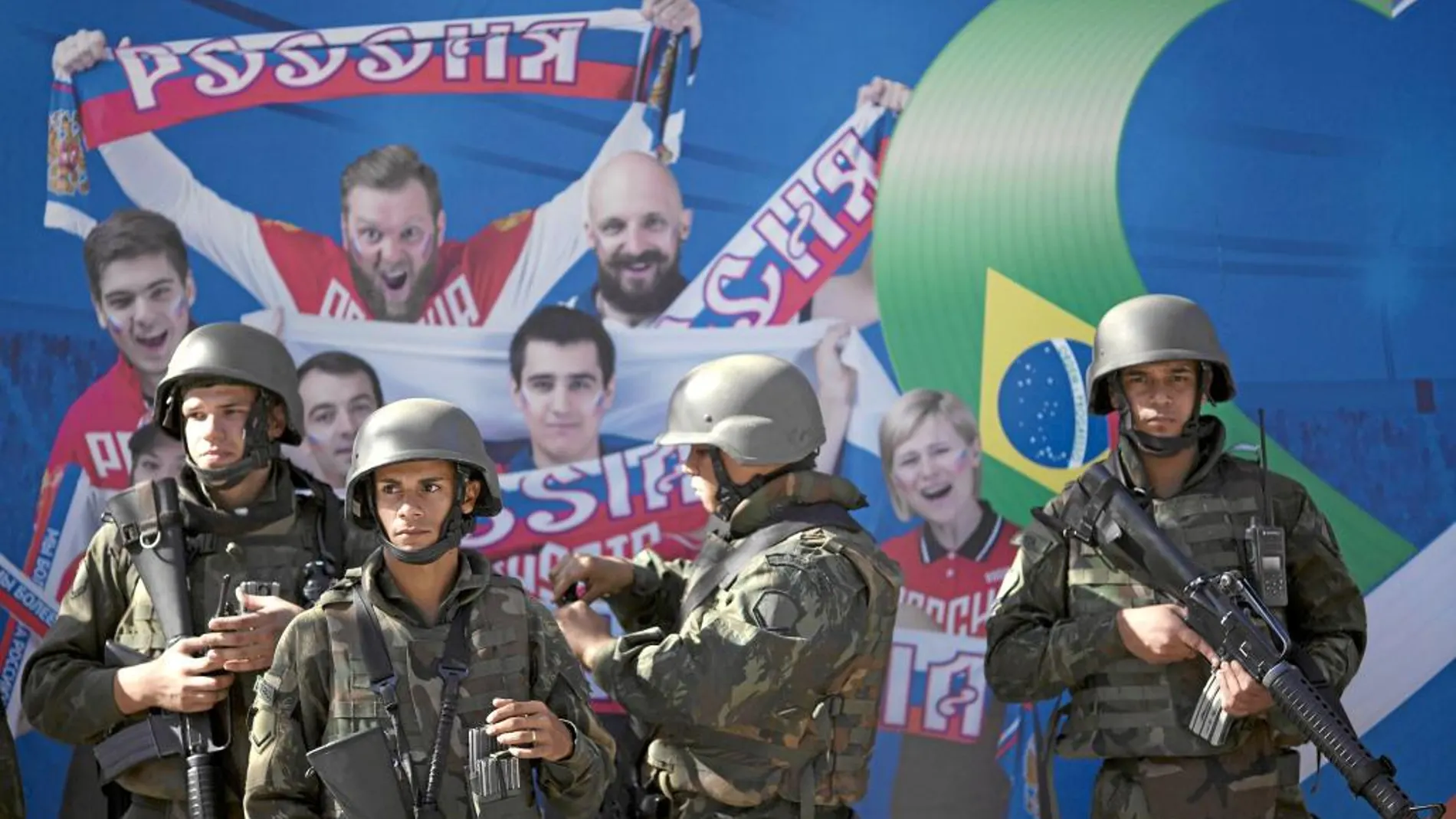 Soldados del Ejército brasileño delante de uno de los murales de Río en el que se muestra a aficionados rusos