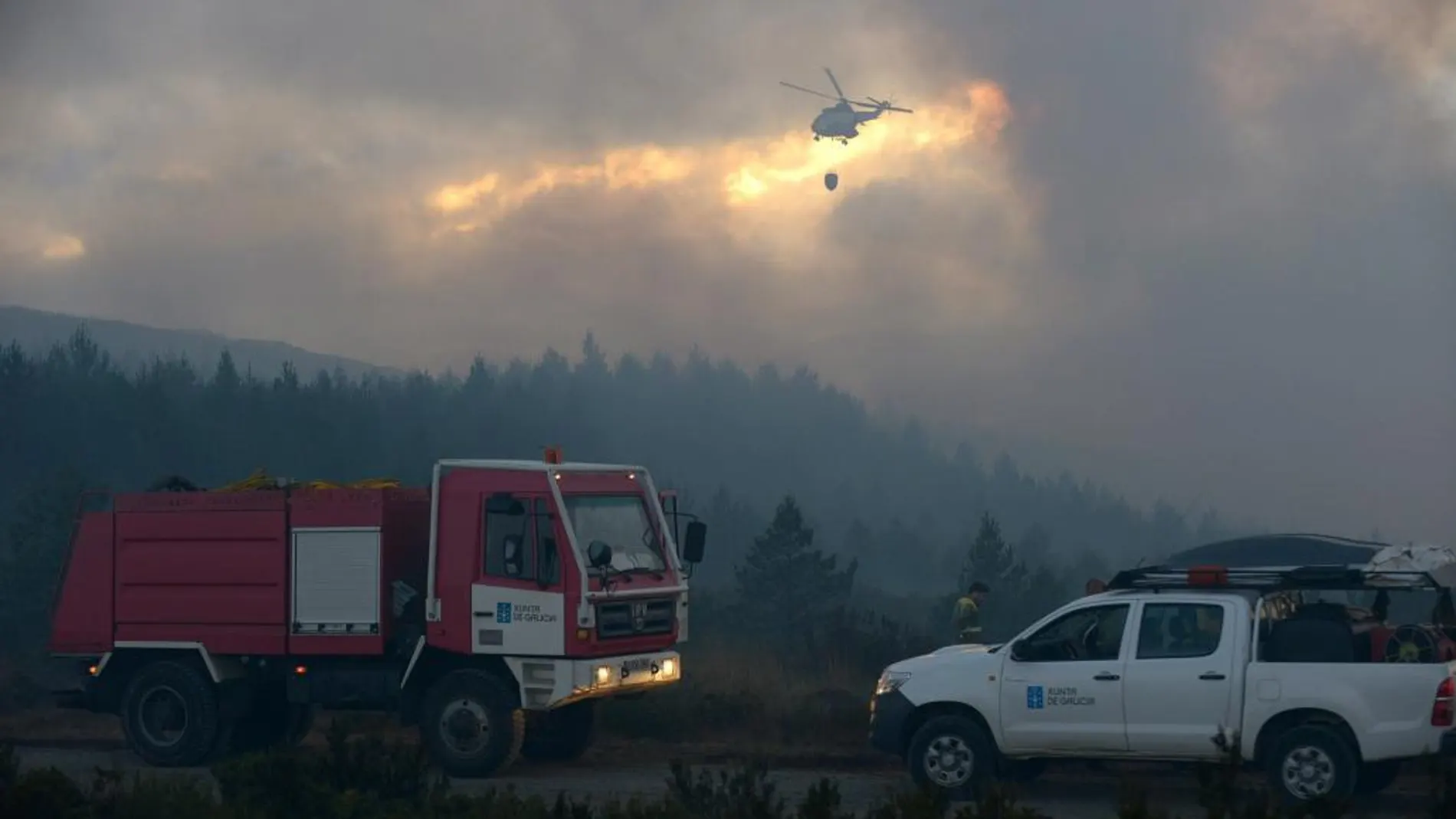 Un helicóptero y dos vehículos contraincendios en la zona afectada por el fuego declarado en Cualedro (Ourense).