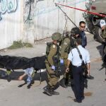 Soldados israelíes trasladan el cuerpo de uno de los palestino muertos en Hebrón