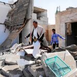 Dos yemeníes caminan entre las ruinas de su vivienda tras los bombardeos de la coalición árabe
