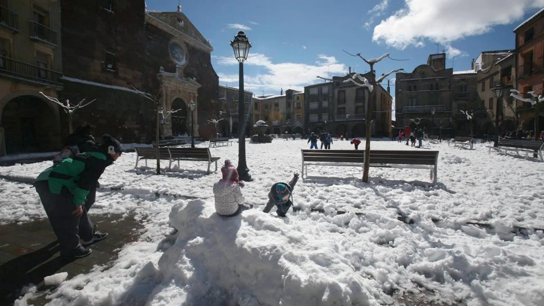 Varios niños juegan con la nieve hoy en una plaza de Prades (Tarragona)