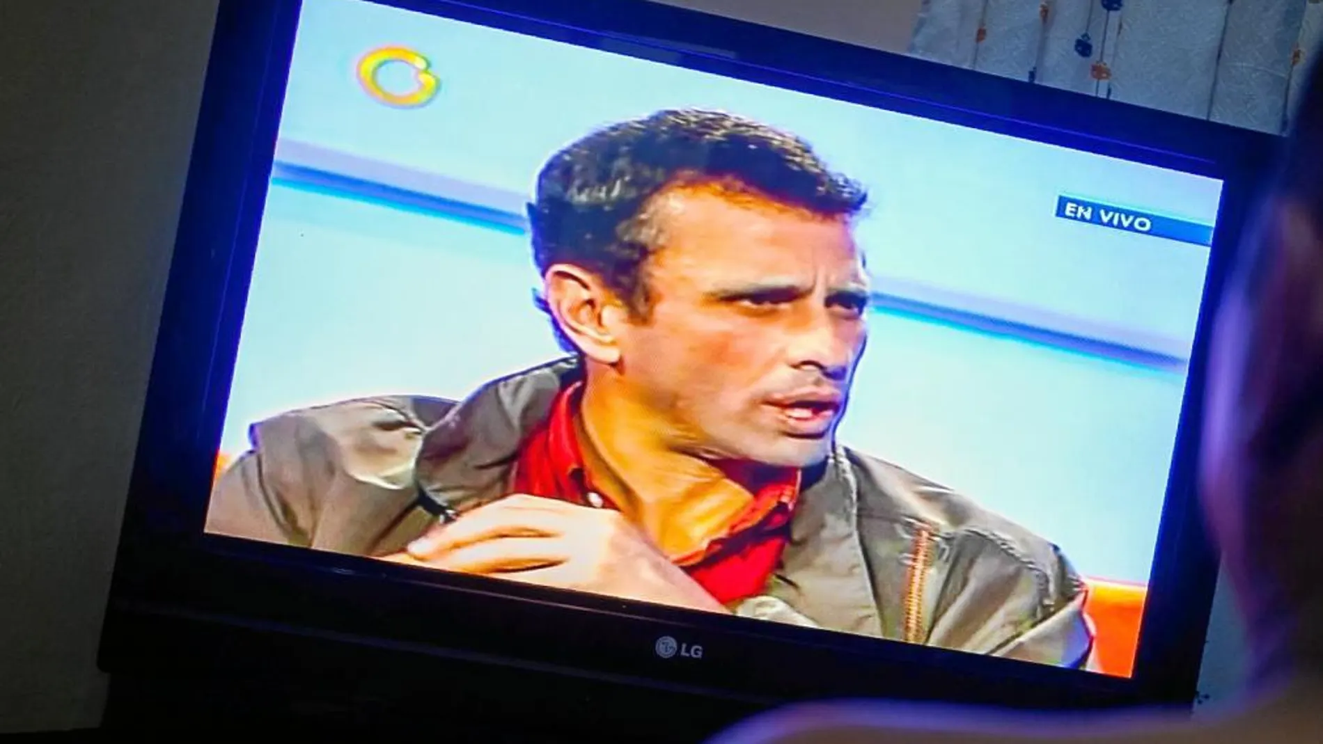 Un hombre observa la transmisión de una entrevista con el canal privado Globovisión al líder de la oposición venezolana, Henrique Capriles,