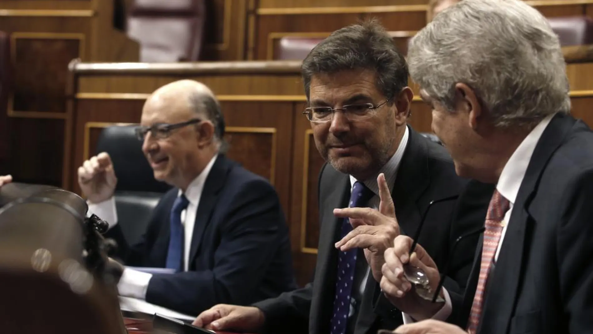 El ministro de Justicia, Rafael Catalá (c), junto al ministro de Hacienda, Cristobal Montoro (i), conversa con el ministro de Asuntos Exteriores, Alfonso Dastis (d).
