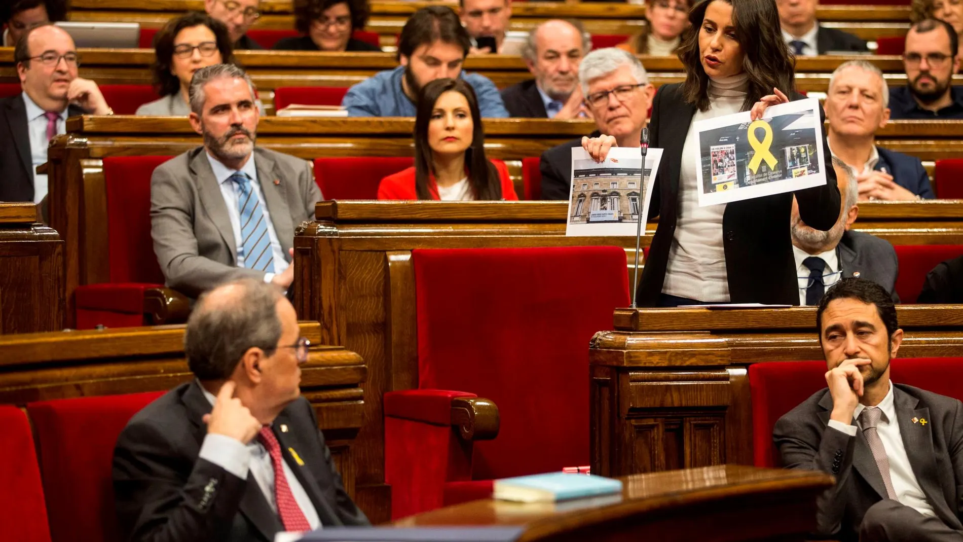 La lider de Ciutadans, Inés Arrimadas, enseña unas fotos de lazos amarillos en edificios públicos al presidente de la Generalitat, Quim Torra (i), durante su intervención en el pleno del Parlament