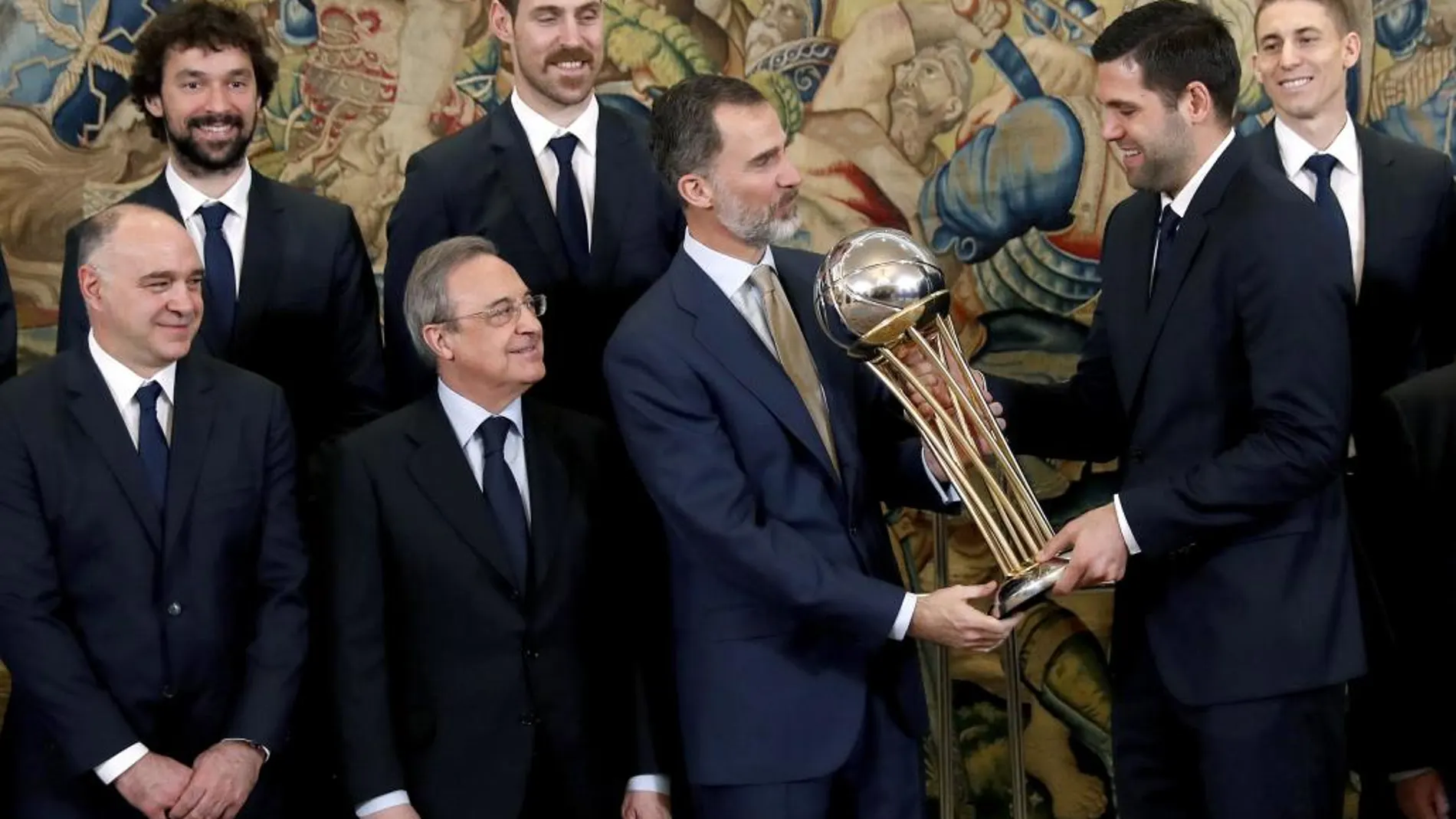 Felipe VI recibe el trofeo de la Copa del Rey de baloncesto de manos del capitán del Real Madrid, Felipe Reyes, en presencia del presidente del club, Florentino Pérez