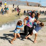 Una familia de migrantes huye de los gases lacrimógenos en la frontera entre México y Estados Unidos