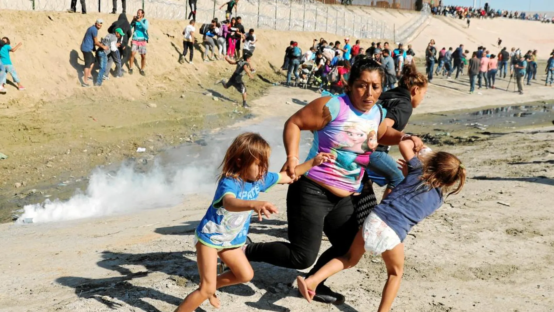 Una familia de migrantes huye de los gases lacrimógenos en la frontera entre México y Estados Unidos