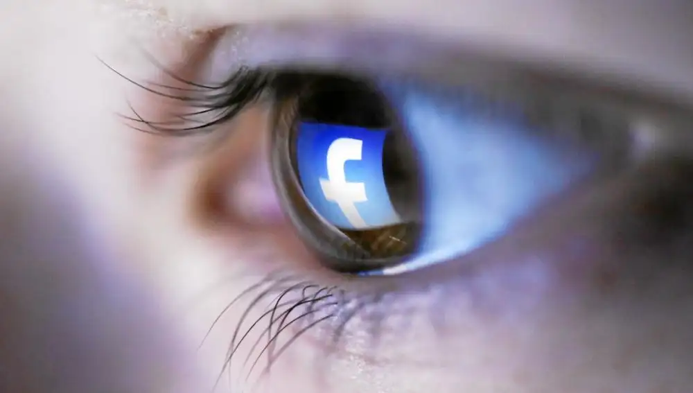 El logo de Facebook, reflejado en el ojo de una joven que navega por la red social