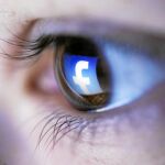 El logo de Facebook, reflejado en el ojo de una joven que navega por la red social