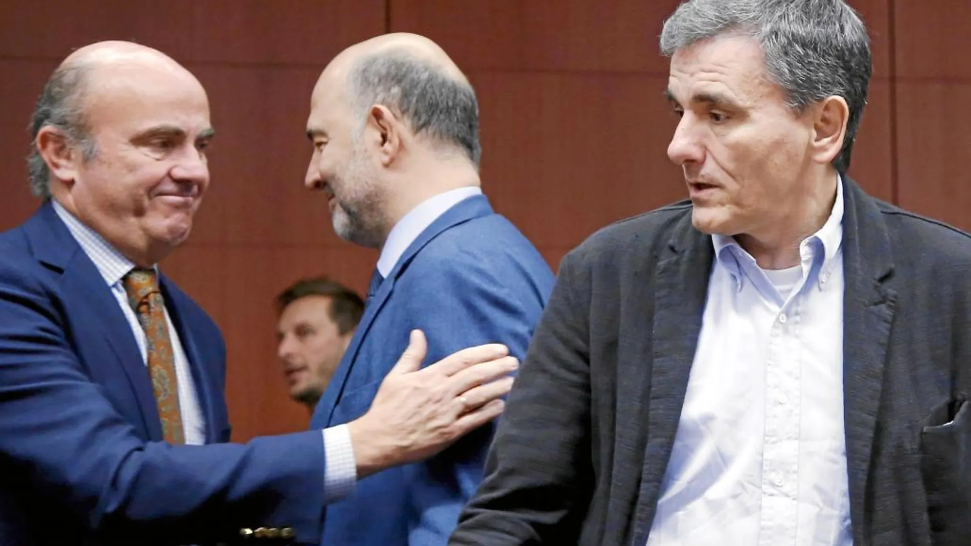 Luis de Guindos saluda al comisario de Finanzas, Pierre Moscovici, en presencia del griego Euclides Tsakalotos