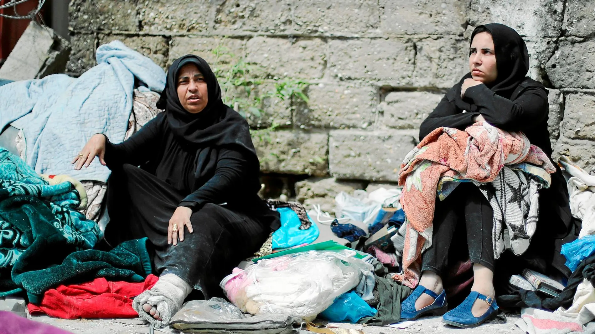 Las más vulnerables. Dos mujeres sentadas en la calle con sus pertenencias tras ser destruida su casa por ataques israelíes. Foto: Reuters