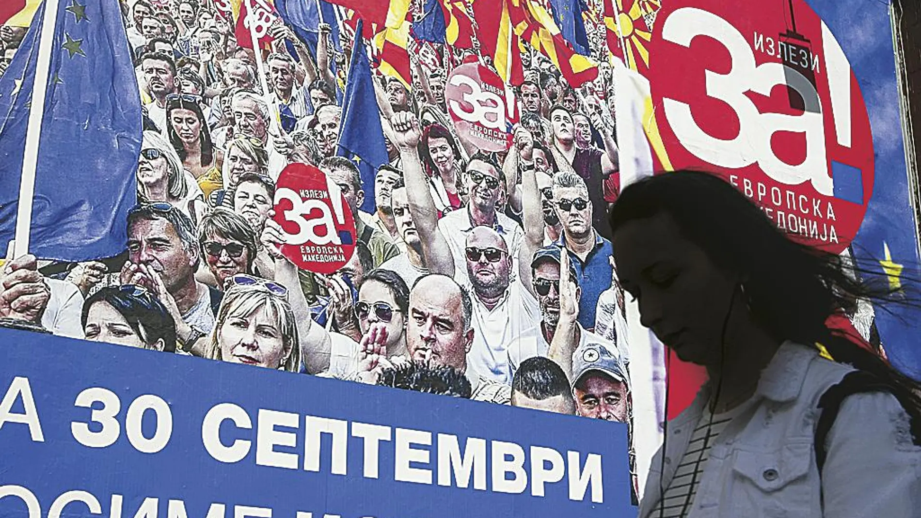 Una mujer pasa por delante de un cartel electoral en la capital, Skopje, en el que se pide el voto del «sí» para que Macedonia pueda entrar en la UE