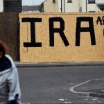Una mujer pasa cerca de un grafiti que señala al IRA como una organización acabada