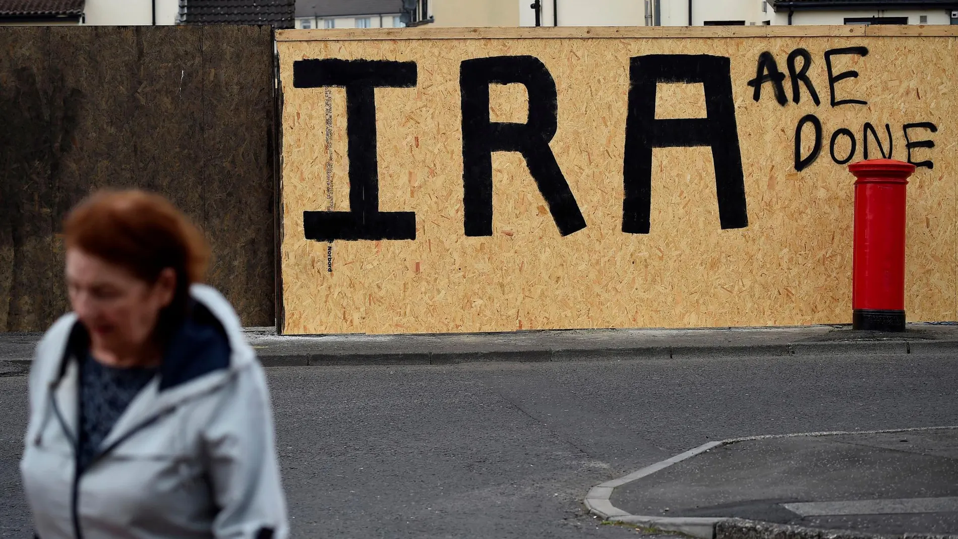 Una mujer pasa cerca de un grafiti que señala al IRA como una organización acabada