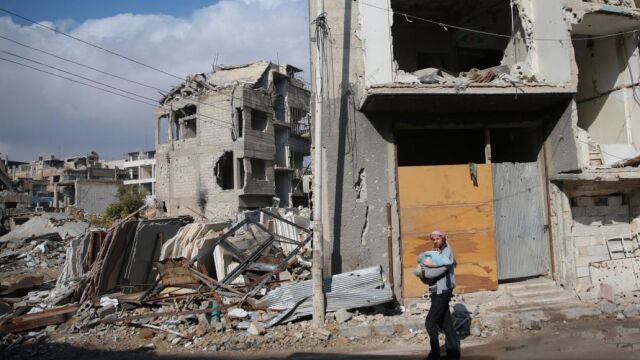 Un hombre camina el día 30 de diciembre con un bebe en brazos en la zona rebelde de la ciudad Douma