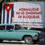 Un coche pasa junto a un cartel alusivo al bloqueo de Estados Unidos contra Cuba, en La Habana (Cuba)