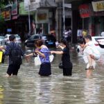 Un grupo de personas trata de cruzar una calle inundada por el temporal