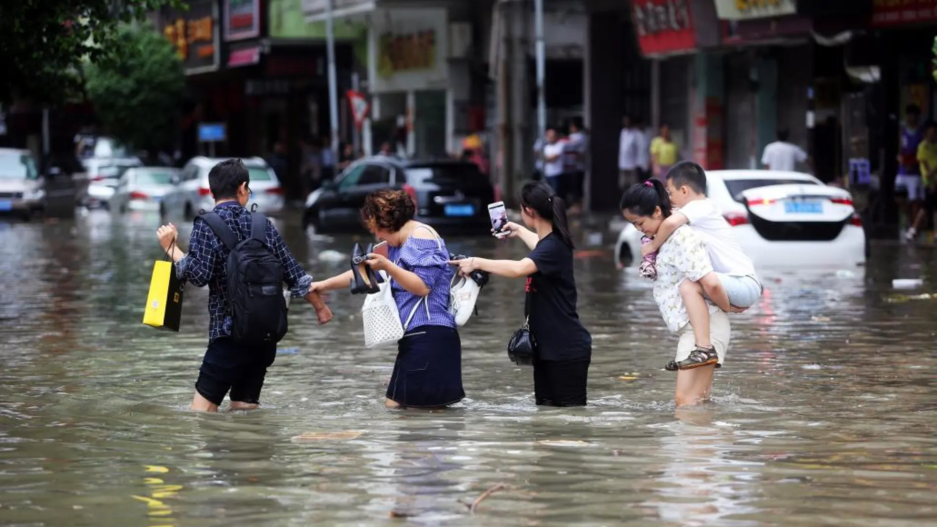 Un grupo de personas trata de cruzar una calle inundada por el temporal