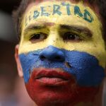 Un opositor venezolano pide libertad con la cara pintada con los colores de la bandera venezolana/AP