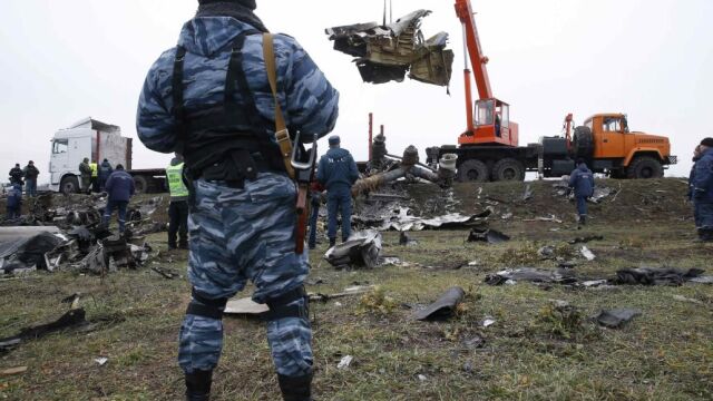 Un miliciano prorruso oserva como una grúa traslado los restos del vuelo MH17, abatido en la región de Donetsk, en el este de Ucrania.