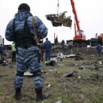 Un miliciano prorruso oserva como una grúa traslado los restos del vuelo MH17, abatido en la región de Donetsk, en el este de Ucrania.