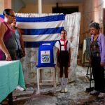 Funcionarios cubanos cantan el himno nacional antes de la apertura de las urnas durante la jornada electoral de ayer, en La Habana