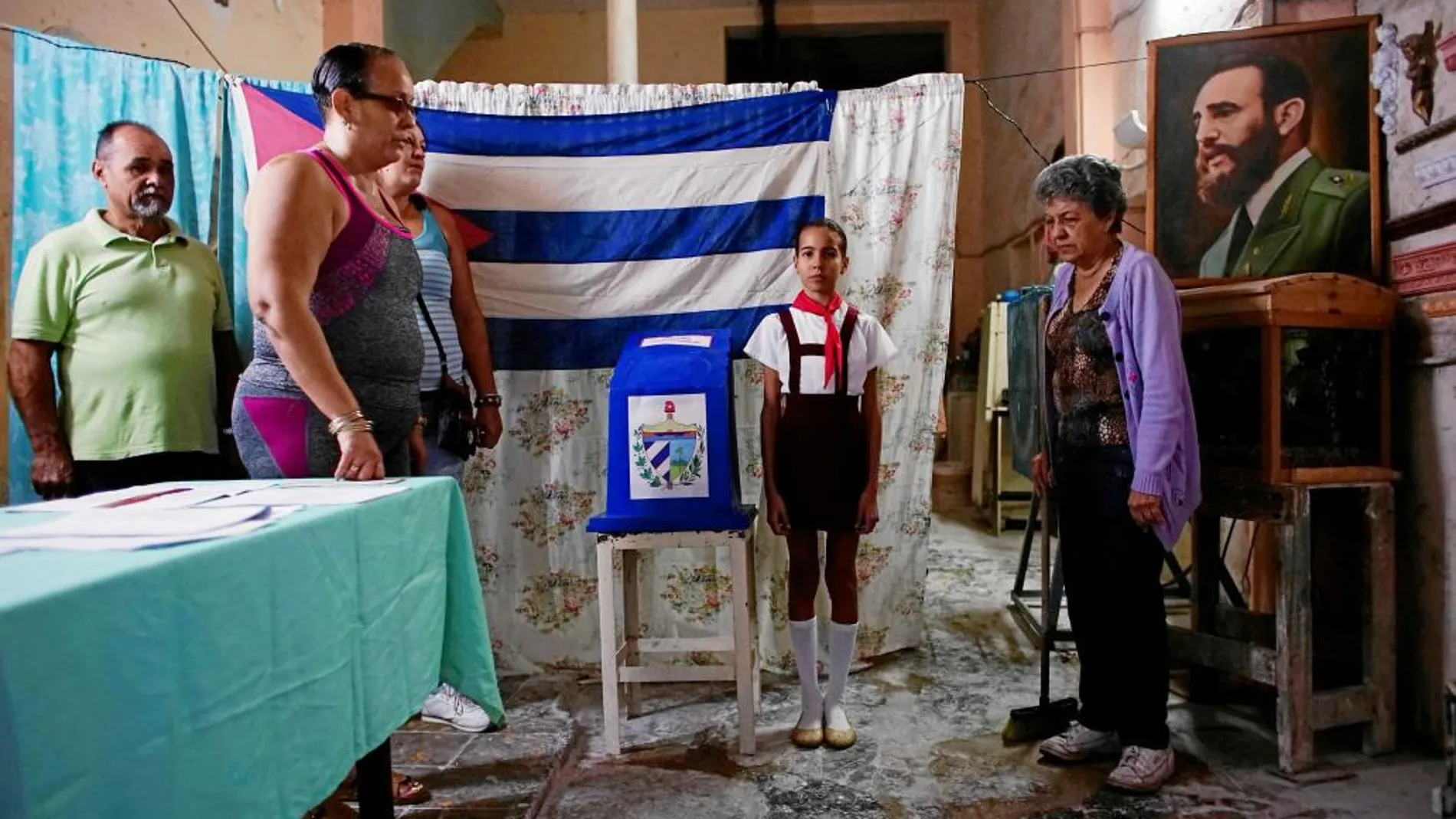 Funcionarios cubanos cantan el himno nacional antes de la apertura de las urnas durante la jornada electoral de ayer, en La Habana