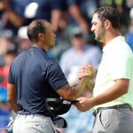 Jon Rahm y Tiger Woods se dan la mano tras la primera jornada