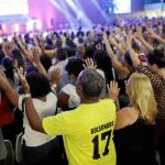 Fieles evangelicos, uno de ellos con una camiseta a favor del candidato ultra, asisten a un servicio religioso de Silas Malafaia en Río de Janeiro