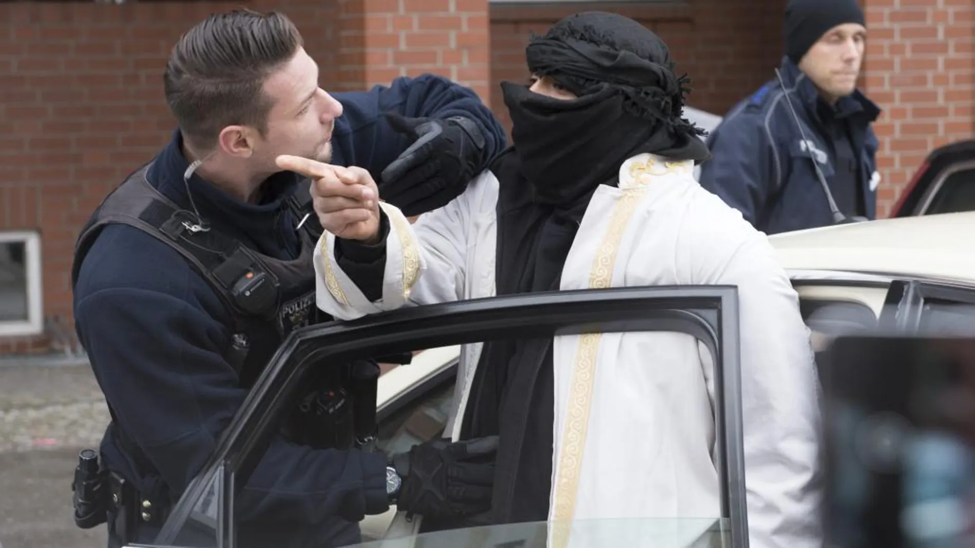 Un agente de policía alemán interroga ayer a un hombre con el rostro tapado antes de subirse en un taxi frente a una mezquita en la calle Perleberger en Berlín (Alemania