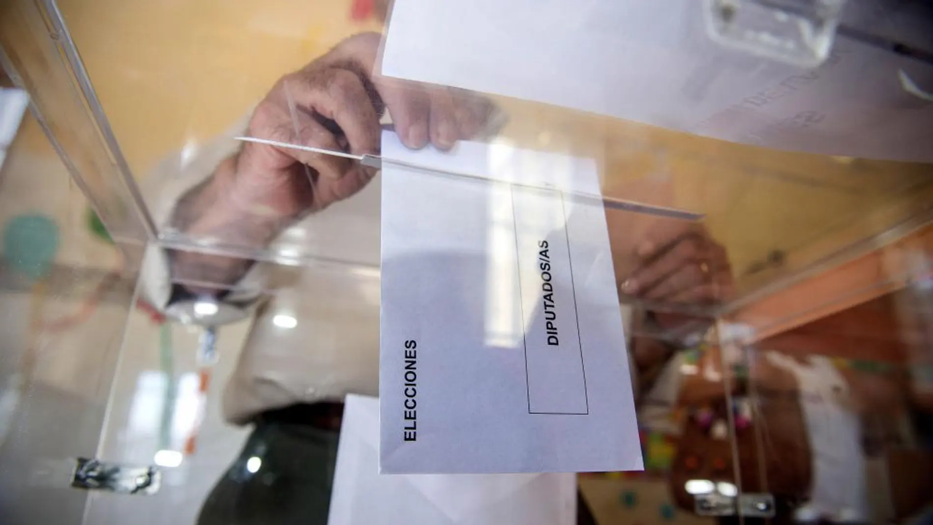 Una persona deposita en una urna de un colegio electoral