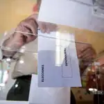 Una persona deposita en una urna de un colegio electoral