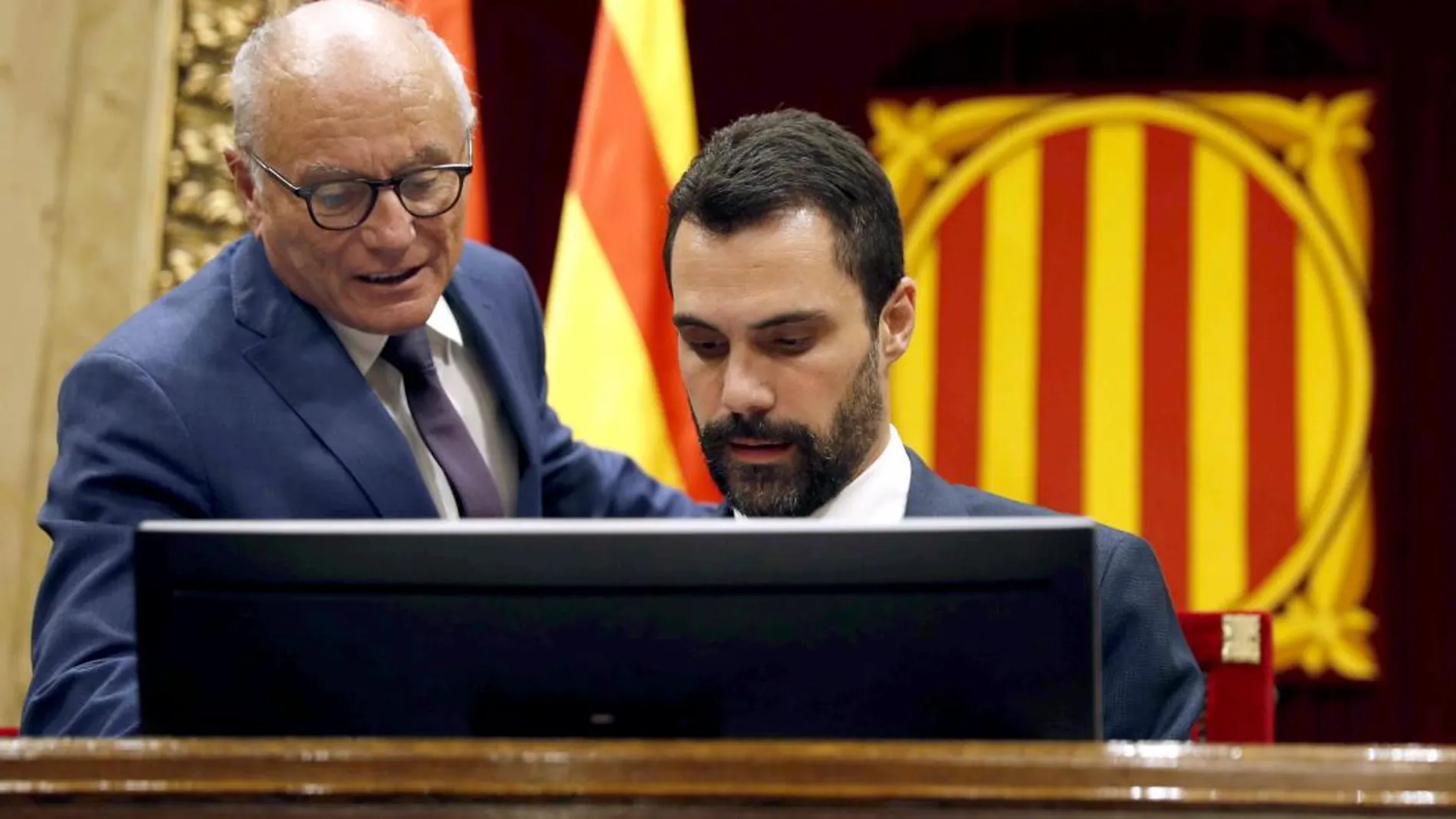 El presidente de la cámara catalana, Roger Torrent (d) habla con el letrado Xavier Muro al inicio del pleno del Parlament. EFE/Toni Albir