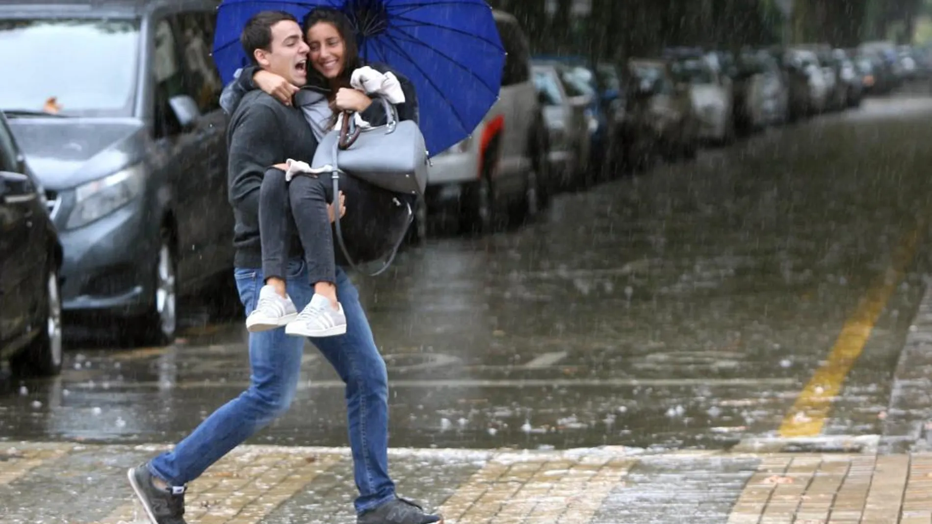 Una pareja cruza una calle de Salou inundada a causa del frente que esta azotando Cataluña
