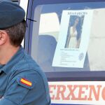 Un agente de la Guardia Civil junto al cartel de búsqueda de Diana Quer, desaparecida en la madrugada del 22 de agosto