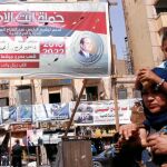 Varias personas caminan por una calle de El Cairo junto a un cartel con la imagen del presidente egipcio Al Sisi