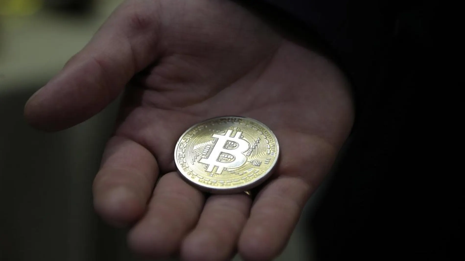 Un hombre sostiene una moneda de bitcoin