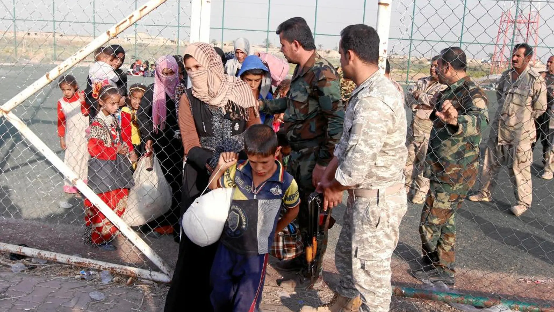Soldados kurdos ayudan a desplazados a su llegada a un campo de refugiados a las afueras de Kirkuk, en Irak