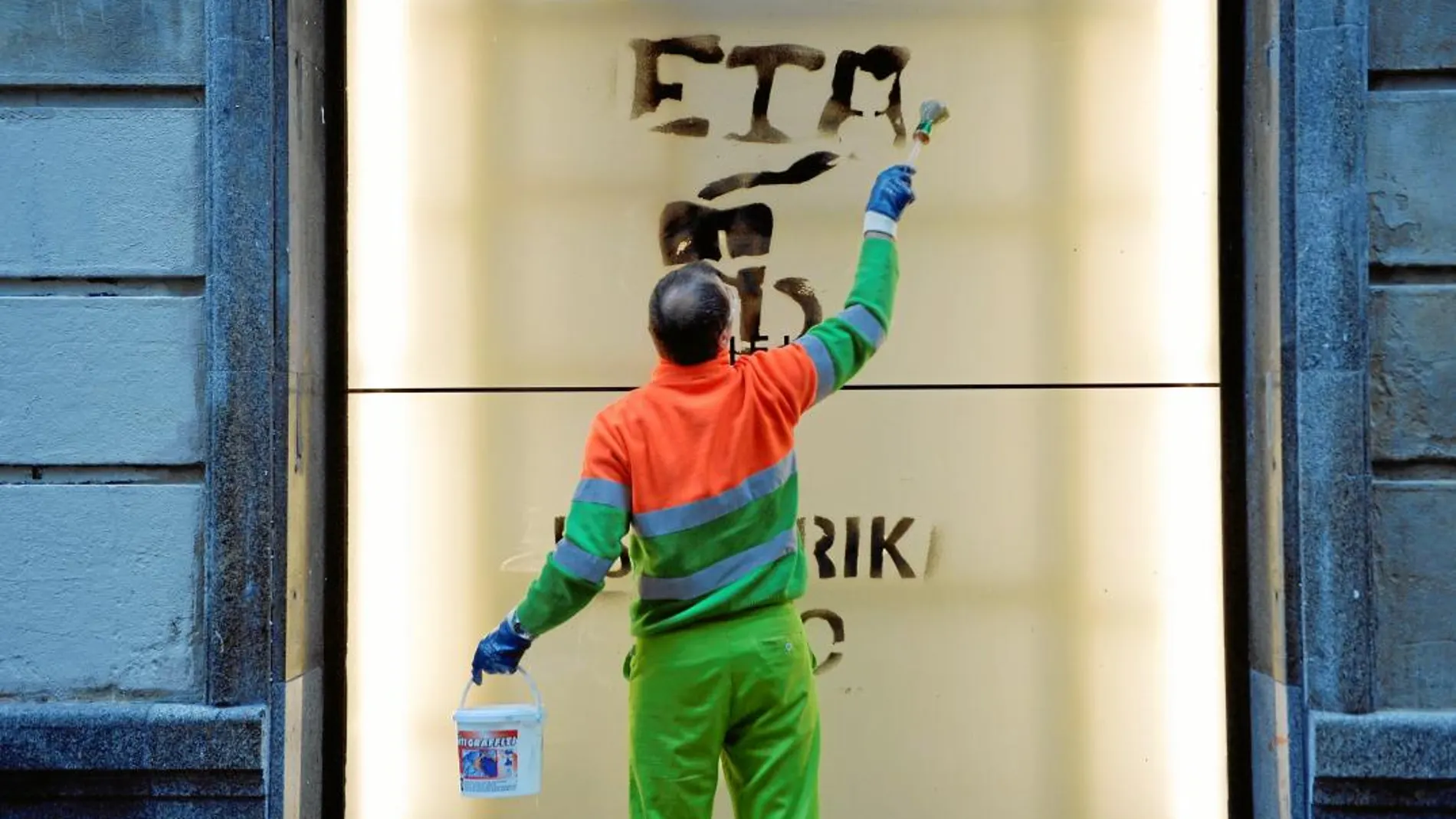 Un trabajador de limpieza borra la pintada de «gracias, ETA» en una calle de Bilbao