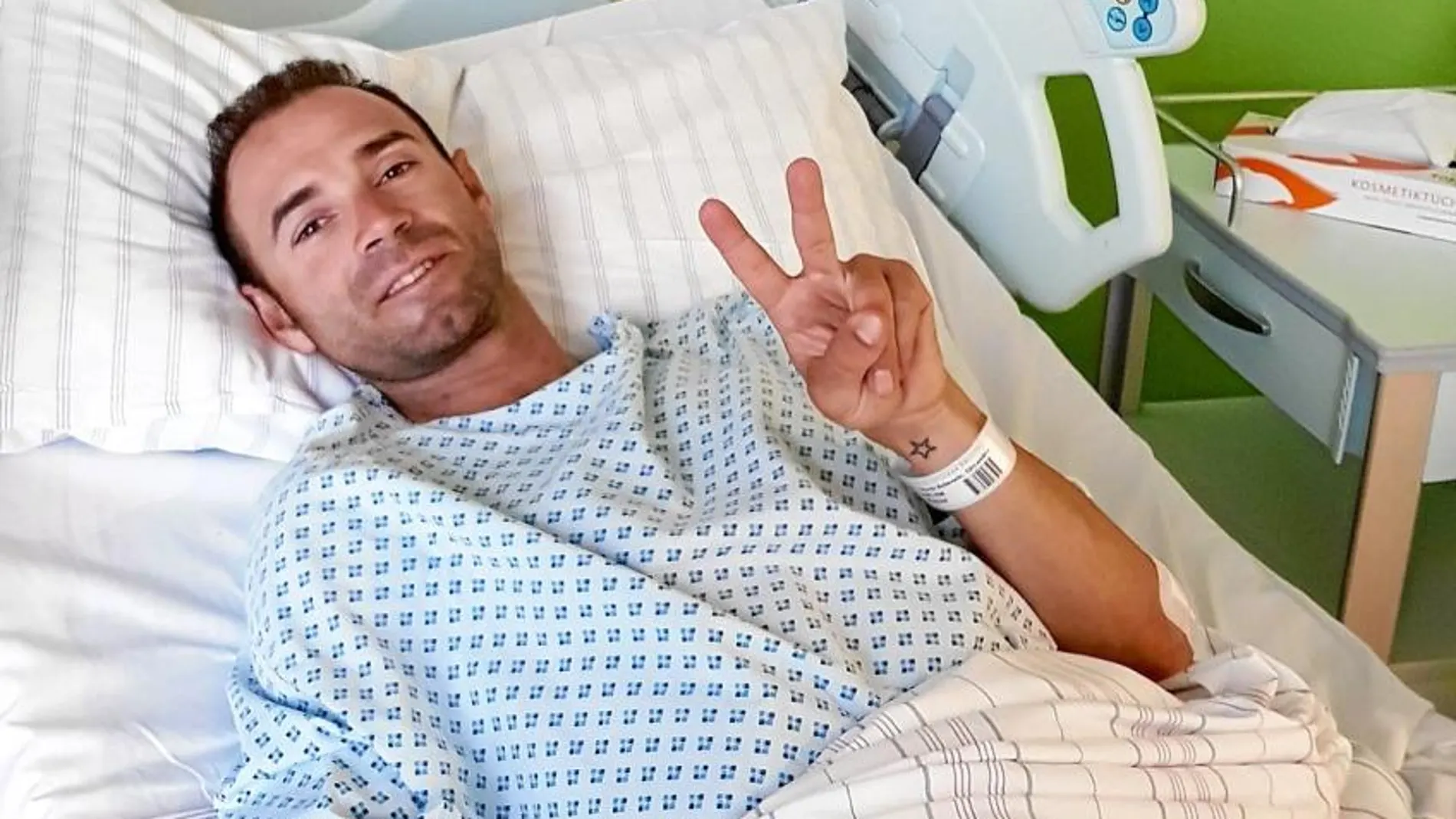 Valverde hace el signo de la victoria tras ser operado de una fractura en la rótula en Düsseldorf. El ciclista murciano se recupera bien.