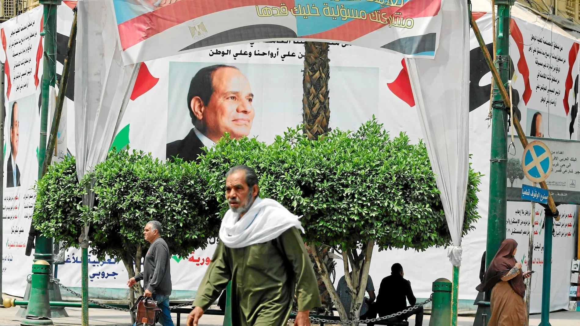 Varios transeúntes pasan junto a un cartel electoral del presidente Abdelfatah Al Sisi para el referéndum constitucional de la próxima semana
