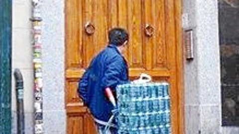 Un latero descargando palés a las puerta de un portal