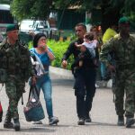 Soldados colombianos acompañan a un policía venezolano, que carga a su hija, y a su esposa, tras desertar, el miércoles en el puente Simón Bolívar, en Cúcuta/Efe
