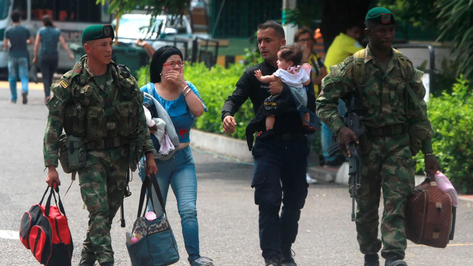 Soldados colombianos acompañan a un policía venezolano, que carga a su hija, y a su esposa, tras desertar, el miércoles en el puente Simón Bolívar, en Cúcuta/Efe